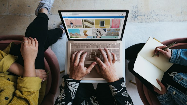 person using microsoft surface laptop on lap with two other people