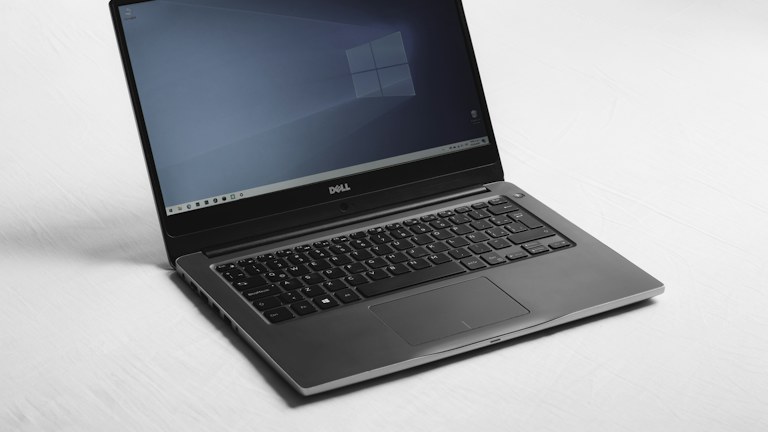 A Dell laptop with a blue desktop screen on a white surface