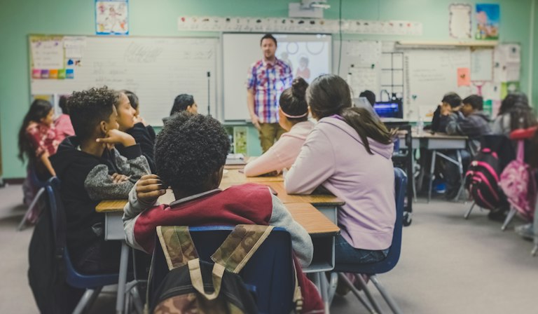 Illustrative classroom with desks and a teacher at the front