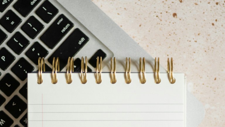 a notepad sitting on top of a laptop computer next to a keyboard